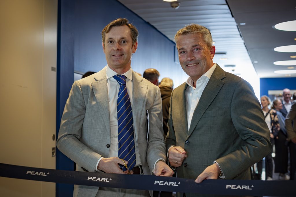 Two business leaders cutting a Pearl‑branded ribbon at the opening of the Pearl Lounge at Copenhagen Airport, with guests in the background.