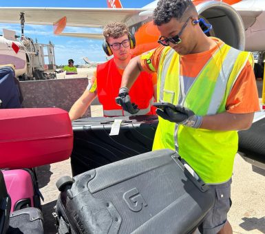 Ground crew scanning and tagging luggage beside an aircraft during apron operations.