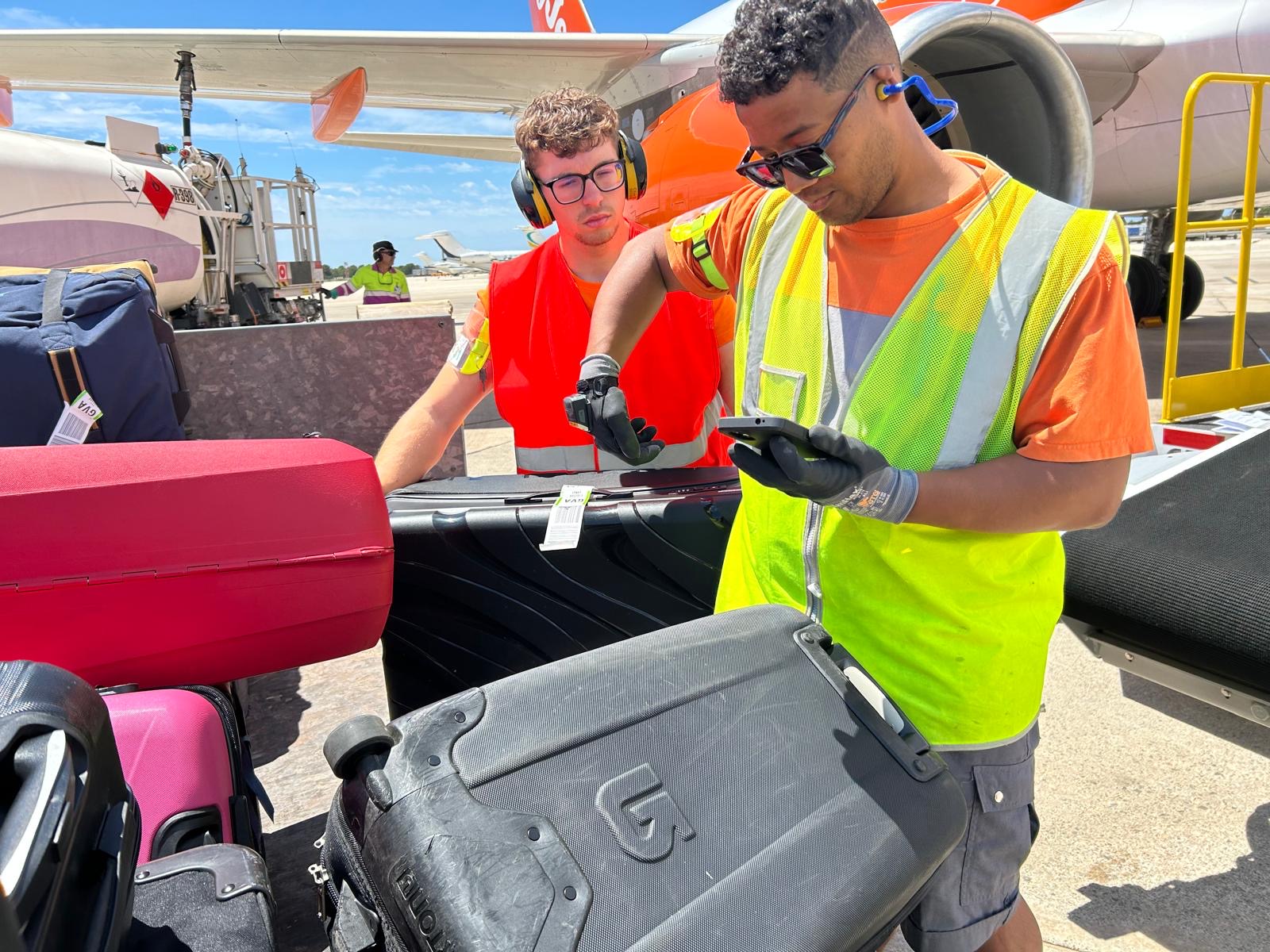 Ground crew scanning and tagging luggage beside an aircraft during apron operations.