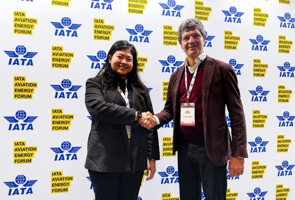 Two event attendees shake hands in front of an IATA Aviation Energy Forum backdrop