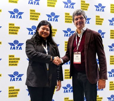 Two event attendees shake hands in front of an IATA Aviation Energy Forum backdrop