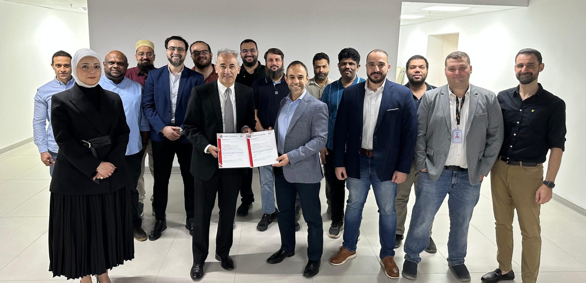 Kuwait team members gathered indoors holding an ISO certification document.