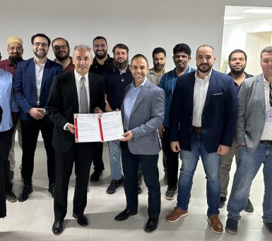Kuwait team members gathered indoors holding an ISO certification document.