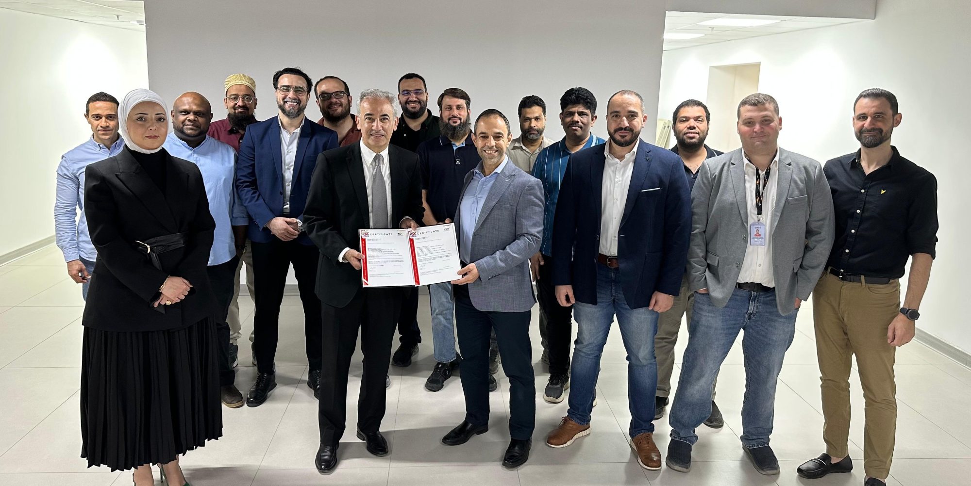 Kuwait team members gathered indoors holding an ISO certification document.