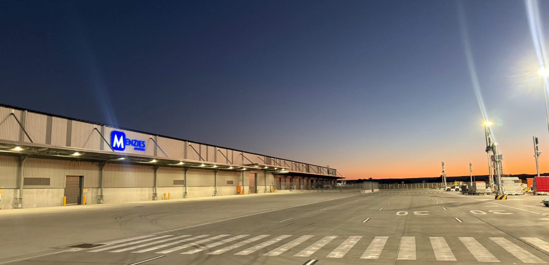 Menzies Aviation cargo facility at Western Sydney International Airport illuminated at dawn.