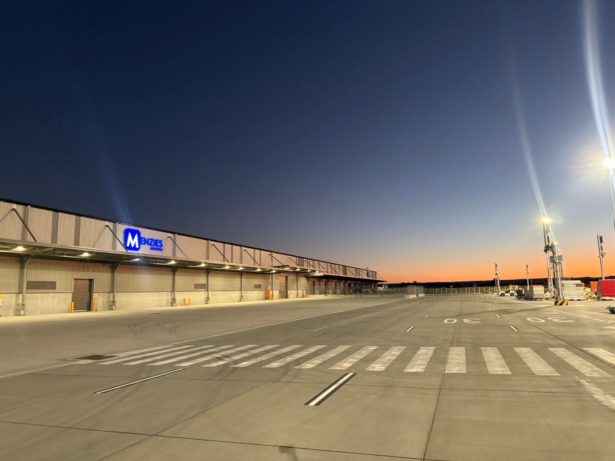 Menzies Aviation cargo facility at Western Sydney International Airport illuminated at dawn.